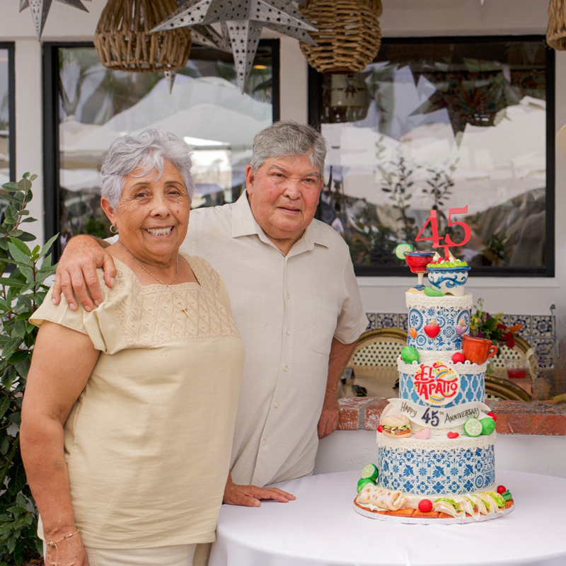 a couple smiling next to a birthday cake